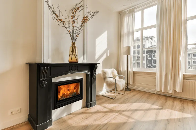 Insert Jidé Nordic Pro 67 encastré dans une cheminée moulurée noire, dans un séjour lumineux au parquet clair