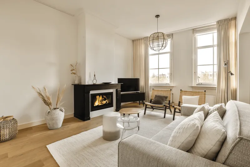 Insert Jidé Nordic Pro 77 dans une cheminée noire, dans un séjour clair avec canapé gris et tapis